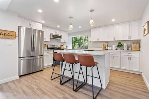 Social cooking space featuring a white island with pendant lights and bar seating.