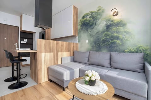 A stylish lounge corner with a comfortable sofa, designer lamp and green wall mural creates a cozy space to unwind after a day full of adventures.
