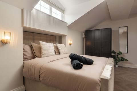 A bright, open-plan studio featuring a king bed, Smart TV with Netflix, a wardrobe, a cosy fireplace, and a dressing table that doubles as a vanity and work desk—ideal for relaxing, working, or getting ready for the day.
