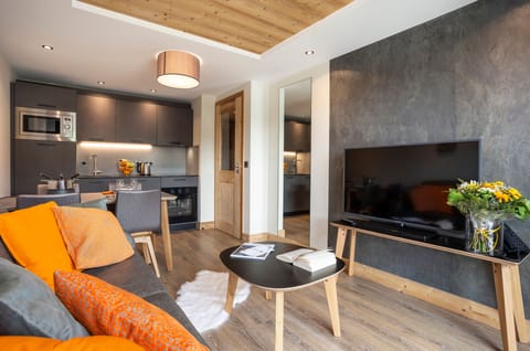 Elegant lounge with bold orange cushions and warm wood finishes, perfect for après-ski comfort.