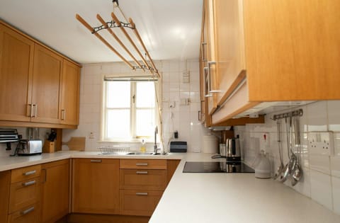 Fitted kitchen with wall and base cupboards, sink, hob, kettle and toaster