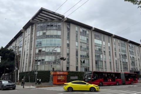Modern building under a cloudy sky, with cars parked nearby