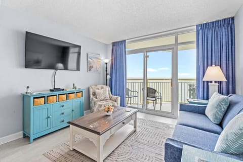 Enjoy gorgeous sunrises and cherish memorable experiences in this 1br 1ba oceanfront resort condo with all the amenities.  This living room is equipped with a Smart TV,  couch, and oceanfront balcony with chairs.  It`s the perfect beachfront escape.