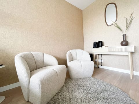 Stylish setup with curved lounge chairs, earthy tones, and a mirror above a coffee console.