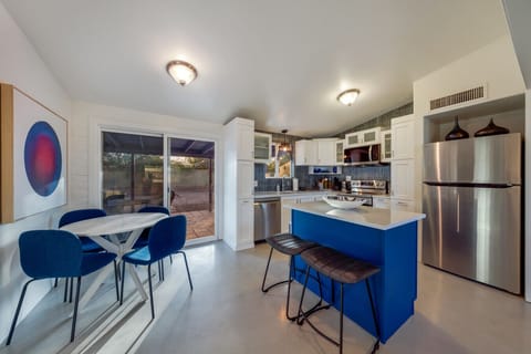 Dining area with seating for four and well-equipped kitchen with stainless steel appliances and island with additional seating