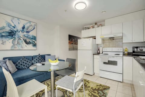 Cozy Living Meets Functionality - Relax in this bright open-plan space featuring a comfy sofa, modern artwork, and a convenient glass dining table, perfect for shared meals and casual lounging.