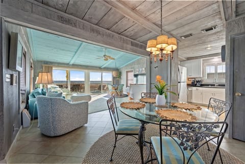 Step into your coastal retreat where rustic charm meets ocean elegance. Dine under warm chandelier light while waves beckon beyond floor-to-ceiling windows.