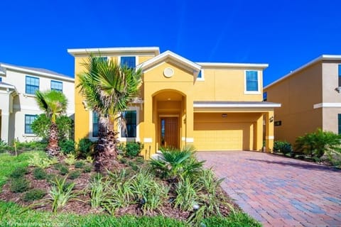 Charming yellow villa with lush landscaping and a welcoming driveway.