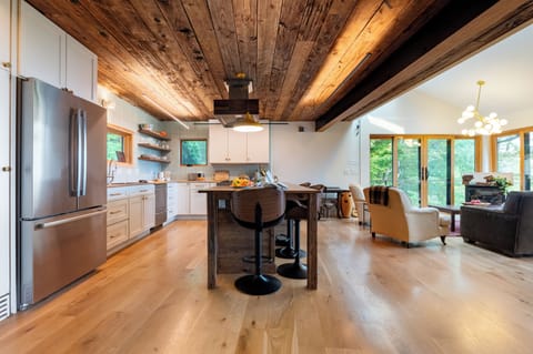 Open concept with high vaulted ceiling with exposed wooden planks and a light hardwood floor.
