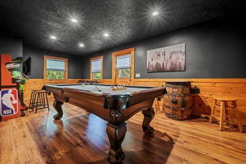 Cozy game room with pool table, arcade game, and rustic cabin style