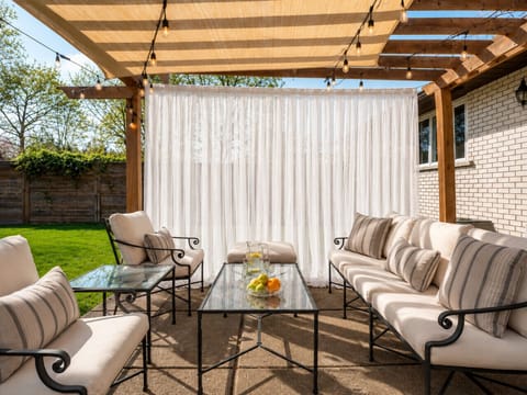 Covered pergola lounge with comfortable seating and a large fenced backyard.