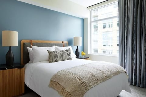Unwind in crisp linens beside bright city-view windows.