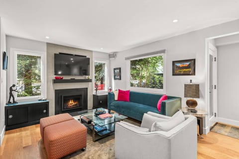 The living room is surrounded by lush landscaping in a quiet residential area