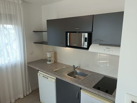 This bright kitchen setup is complete with essential appliances, ample counter space, and a welcoming atmosphere, ideal for your culinary adventures.