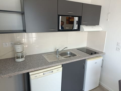 A sleek kitchen area features essential appliances, including a coffee maker and microwave, on a stylish granite countertop.