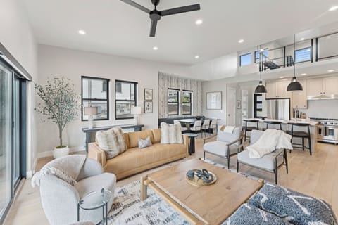 Bright living room and kitchen with island seating and ceiling fan.
