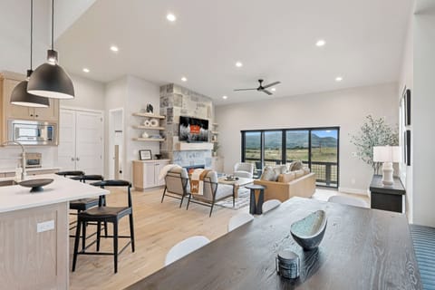 Open-concept kitchen, dining, and living area with island and stools.