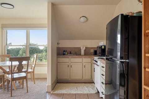 The dining area sits by the window with a round table and four chairs, perfect for meals with a view.