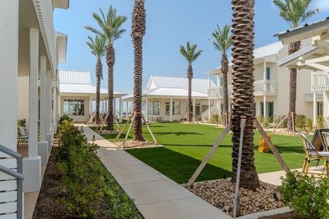 Beautiful courtyard view featuring manicured greenspace, palm trees, and open walkways connecting the bungalows.
