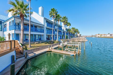 Waterfront property featuring direct canal access with private dock and boat slip under swaying palm trees.