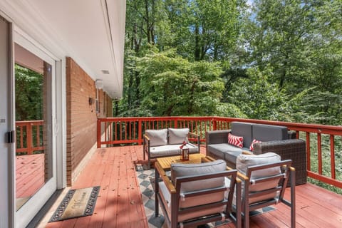 Red‑stained deck with lounge seating and a wooded backdrop—ideal for outdoor meals and relaxing.