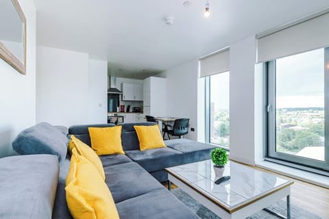 Bright lounge with a comfortable sofa sits next to a sleek kitchen, blending comfort and convenience for both unwinding and preparing meals.