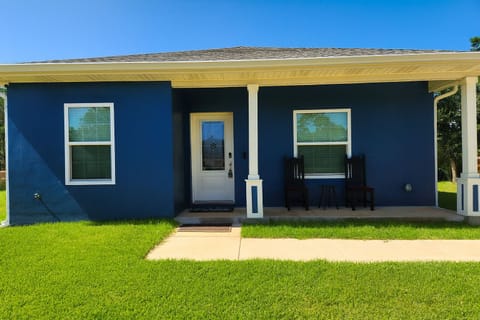 Step up to this inviting front porch, where classic columns and a bold navy exterior set the tone for a relaxing stay.