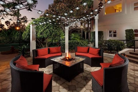 Relax in a serene outdoor space surrounded by lush greenery and comfortable wicker furniture.