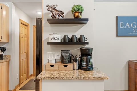 Your morning coffee station awaits with a sleek coffee maker and stylish mugs, perfectly arranged on granite countertops.