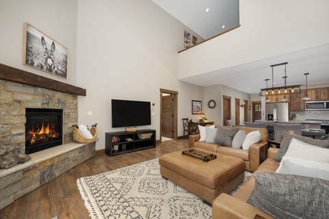 Unwind by your crackling stone fireplace in this open-concept living space, where leather seating and modern amenities create the perfect mountain retreat.