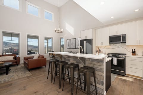 Your modern kitchen flows seamlessly into the living space, featuring soaring ceilings and mountain views that inspire your culinary adventures.