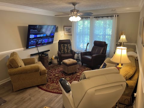 Living room features a 70 inch TV, seating for 7, & full body massage chair  
