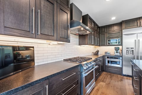 The kitchen with dark wood cabinets, white backsplash and stainless steel appliances.