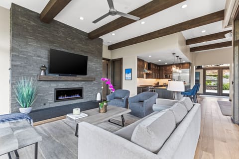 The living room has a light grey colored couch, two dark grey club chairs, and Smart TV.