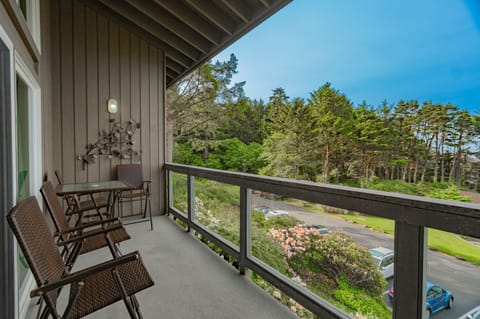 The Forest View Queen Bed Studio features a serene balcony overlooking lush greenery, offering a perfect outdoor setting for relaxation among the trees.
