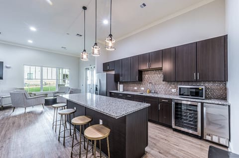Elegant community kitchen featuring granite countertops, bar seating, and cozy lounge space for residents and guests.
