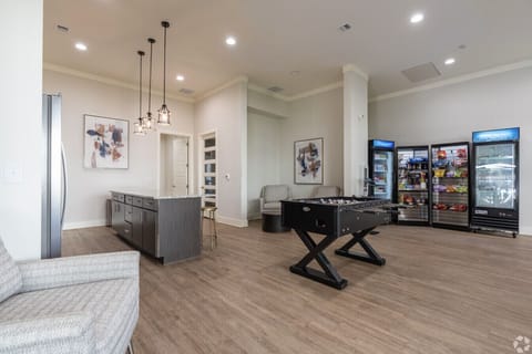 Modern community lounge featuring a foosball table, snack market, and comfortable seating for social time.
