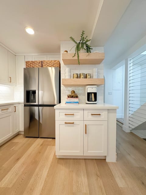 Kitchen with stainless fridge, open shelving, and coffee setup.