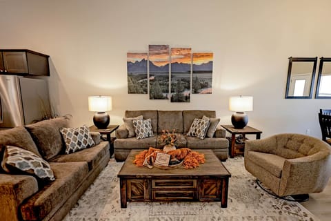 Relax in style—spacious living room with plush seating, modern decor, and sunset views.