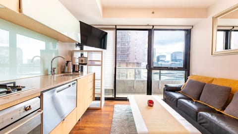 Bright open-plan living area with kitchenette and balcony views of the city skyline