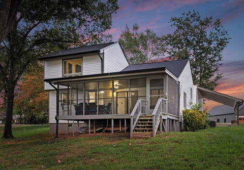 Charming exterior with a screened-in porch, set against a vibrant sunset sky.