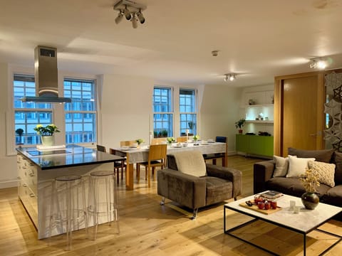 Open plan living area with cosy sofa area, large TV, long dining table & kitchen
