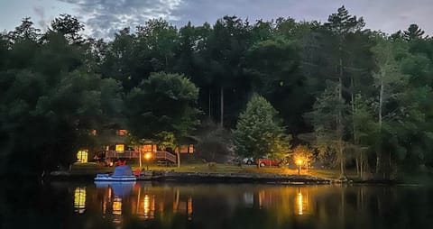Evening view of the house from the lake with the firepit glowing.