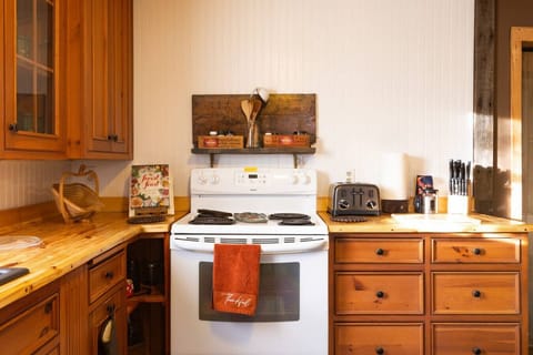 Kitchen Features reclaimed pine wood cabinetry and handmade pine countertops, combining rustic charm with functionality. Fully equipped with a sink, refrigerator, stove, coffee maker, olive oil, salt, pepper, silverware, cookware, dishes, and wine glasses