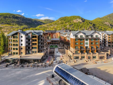 Wide view of multiple buildings with green spaces and mountains.
