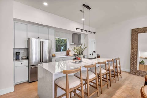 Sleek chef’s kitchen with marble island, designer lighting, and seating for five—perfect for morning coffee, shared meals, and unforgettable evenings.