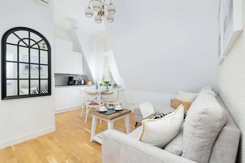 A stylish dining corner with a round table and four chairs. A decorative arched mirror hangs on the wall.