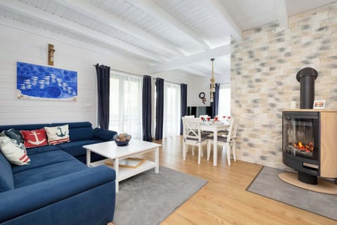A cozy living room with a blue sofa, a fireplace, and a dining table in the background.
