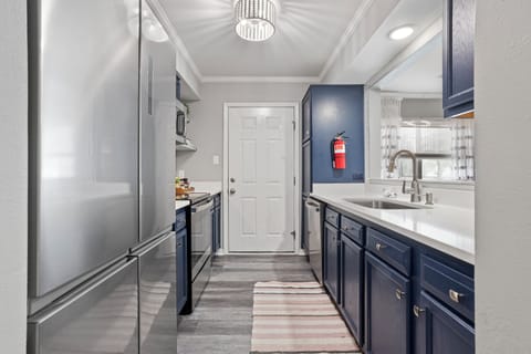 Fully stocked galley kitchen leads to outdoor private patio with grill.