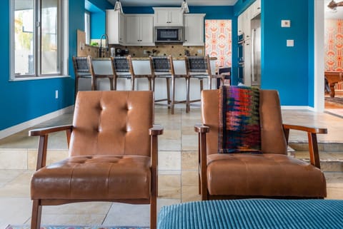 This wide-open space makes it easy for everyone to be together. From the comfy leather chairs to the kitchen bar seating, there's a perfect spot for everyone to grab a drink, have a chat, and feel connected. 